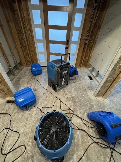 Blue air movers and a dehumidifier drying a stripped floor in a Gresham, OR home